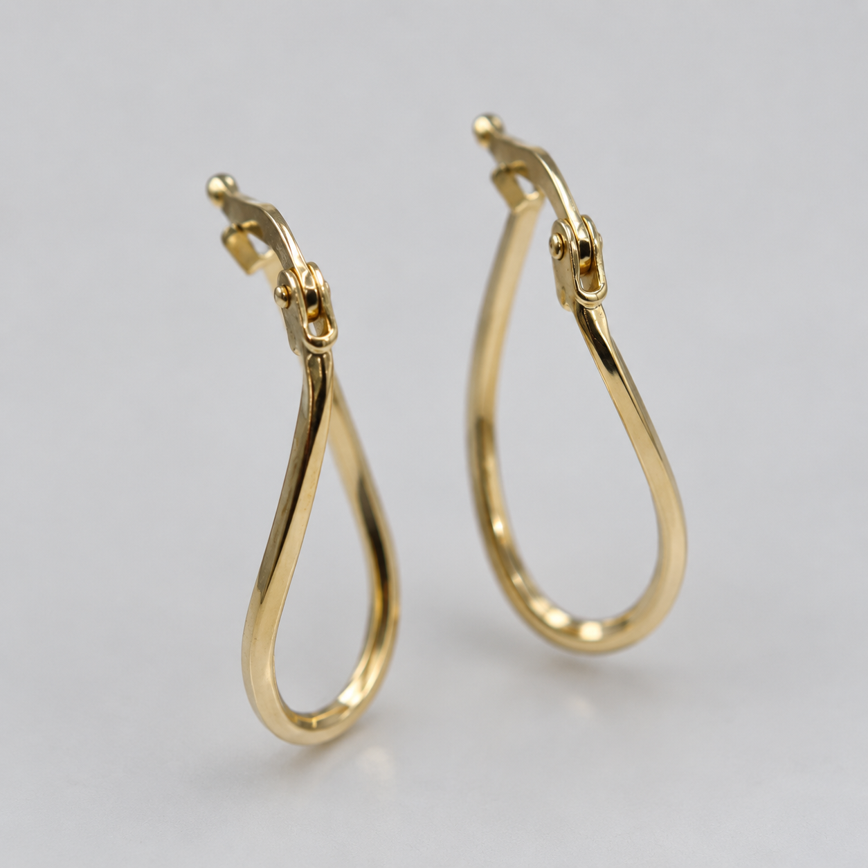 Close up of 9ct gold wavy oval hoop earrings showing hinged snap fitting